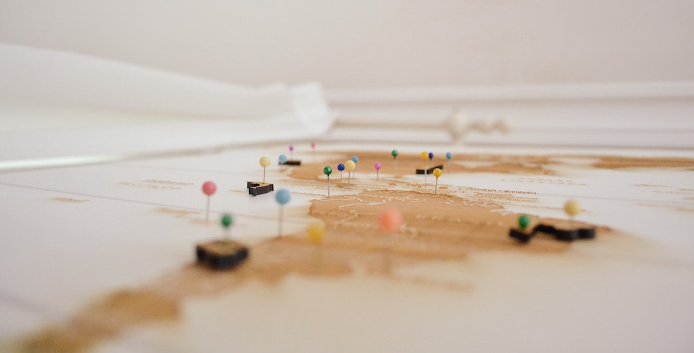 Wooden world map with multi-colored pins in it