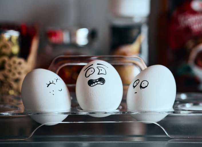 Three eggs with different expressions (happy, mouth agape, scared) drawn on their shells in black marker