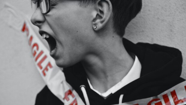 Black and white photo of a teen screaming, wrapped in tape that says "fragile"