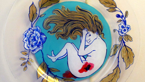 Detail of a glass plate painted with a woman in a fetal position, a bloody fetus in her womb