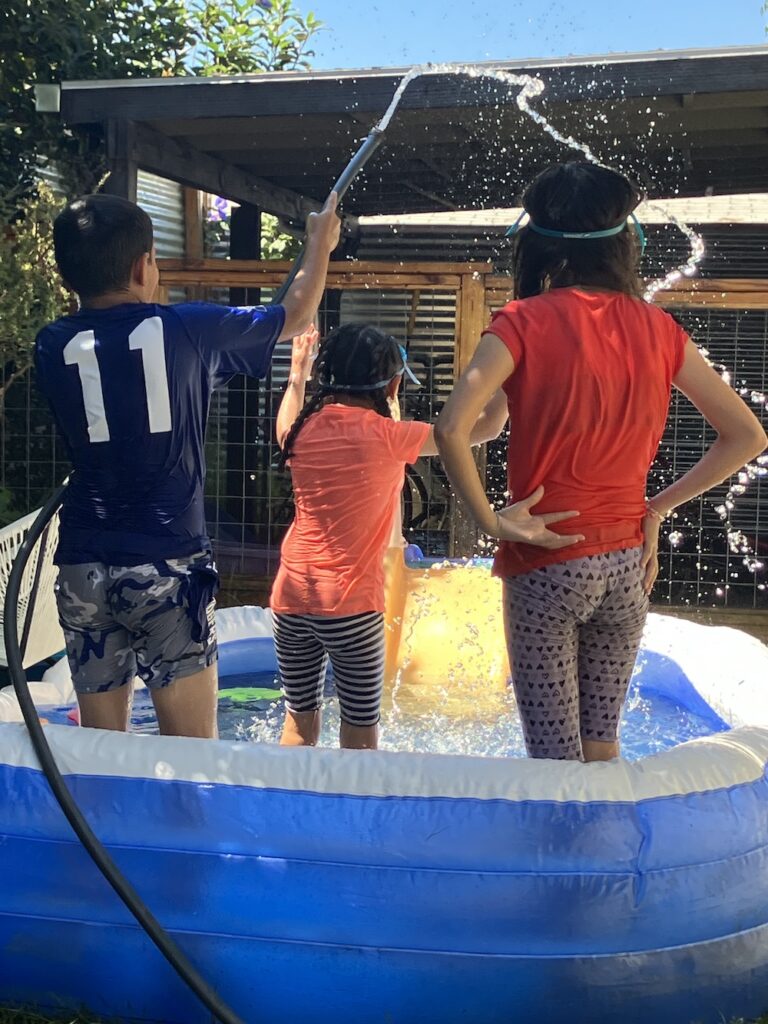 Three children standing in an inflatable pool
