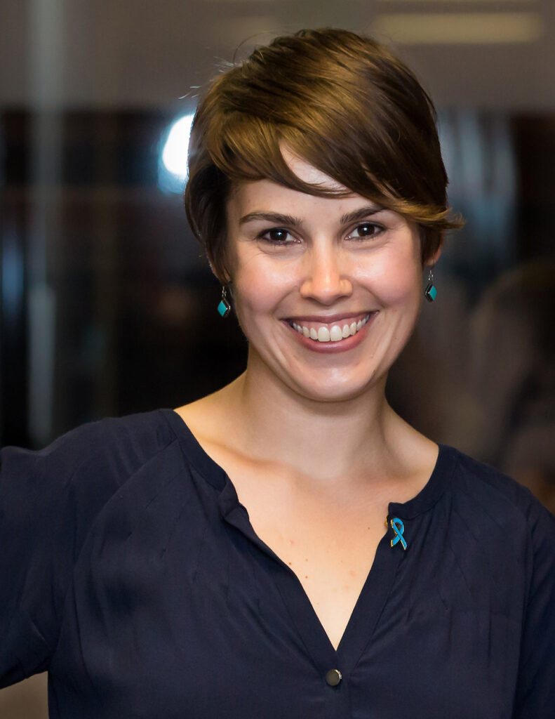 Headshot of a woman with light skin and short auburn hair, smiling