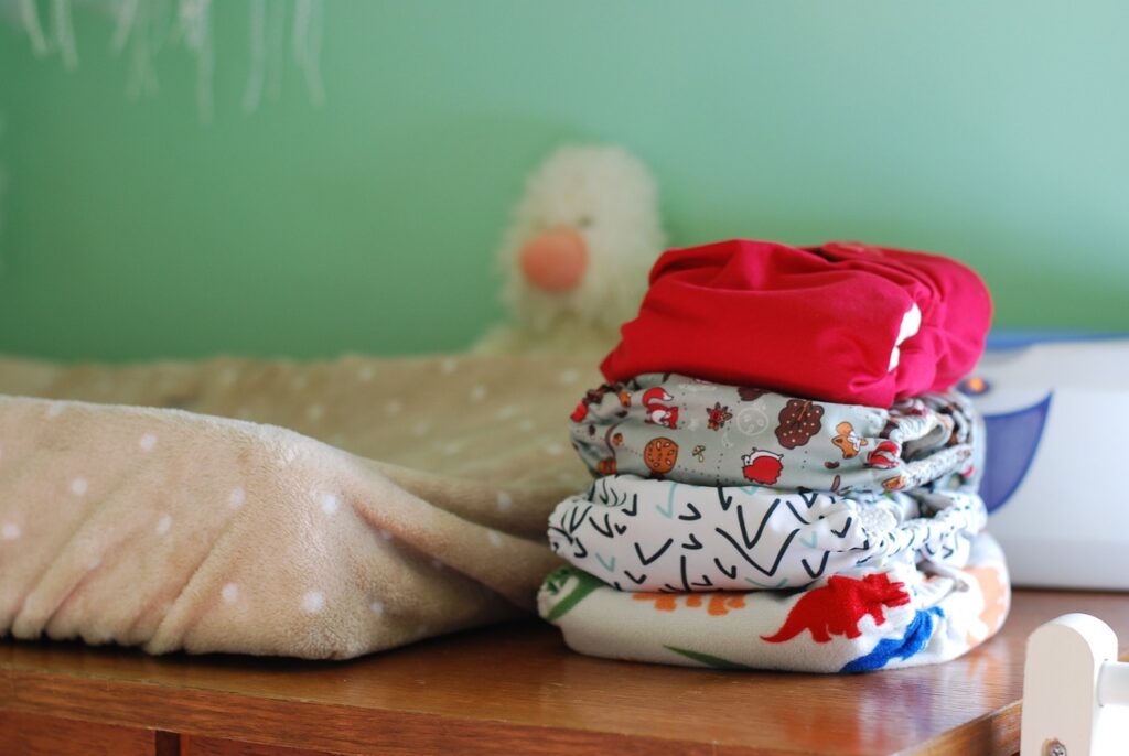 Colorful cloth diapers next to a changing pad