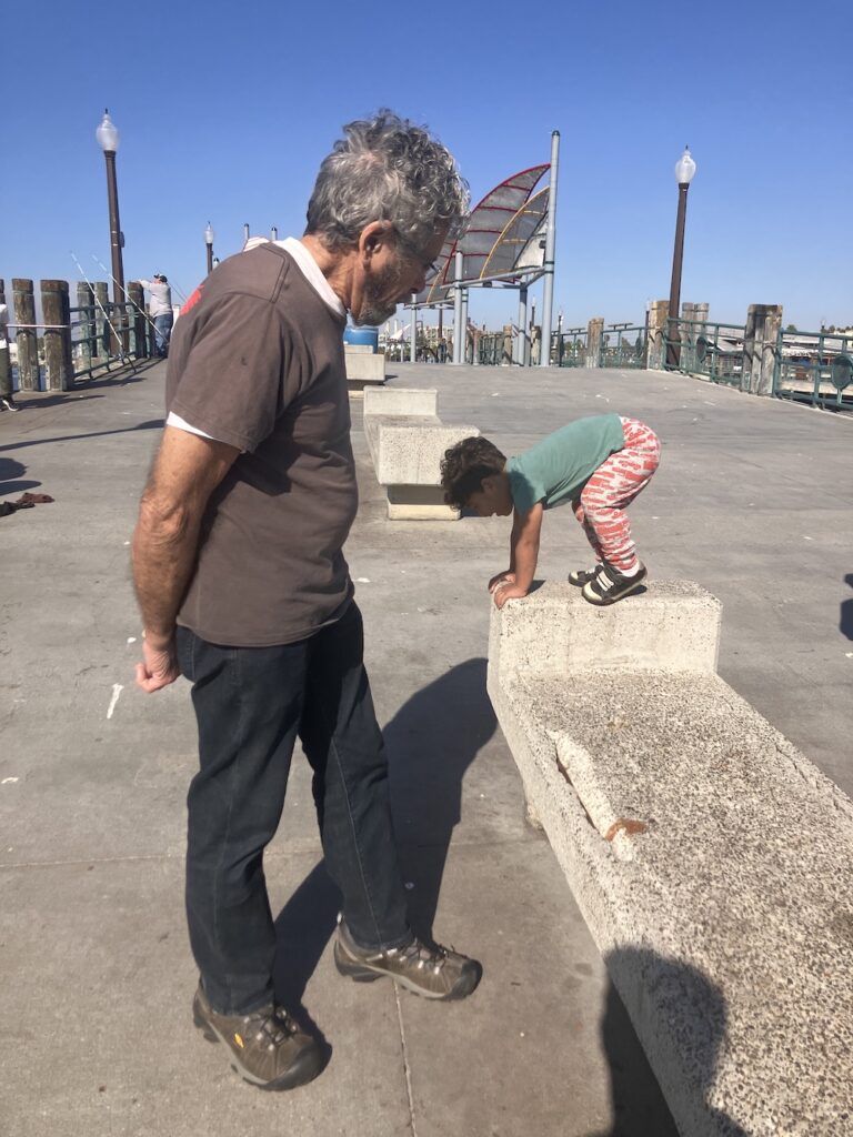 A grandpa and toddler play on a pier