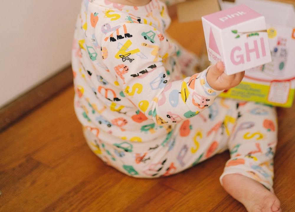 Toddler wearing pajamas and playing with an alphabet block