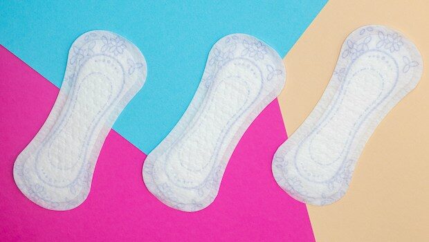 Three menstrual pads against a multicolored background