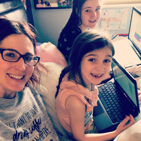 A mom and two daughters who are holding laptops