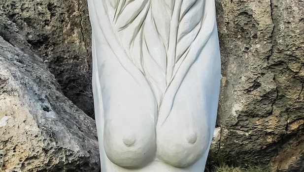 Detail of a statue depicting a woman's breasts with wheat-like stalks growing where her head would be