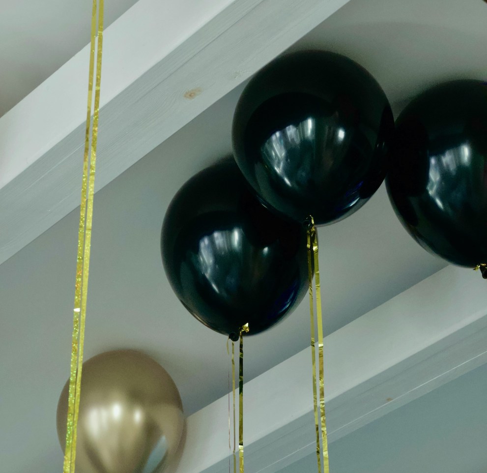 Black and gold balloons touching a ceiling