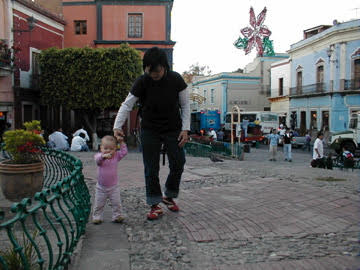A mother leads a toddler down a cobblestone street