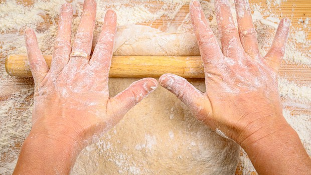 Floured hands rolling out dough