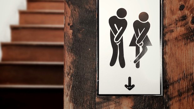 Bathroom sign in which stylized figures hold their hands over their crotches as if they need to pee