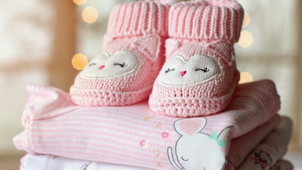 Pink owl booties on top folded pink baby clothes