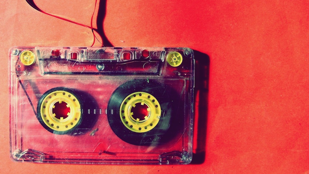 Clear cassette tape against an orange background. Part of the tape has been pulled out.
