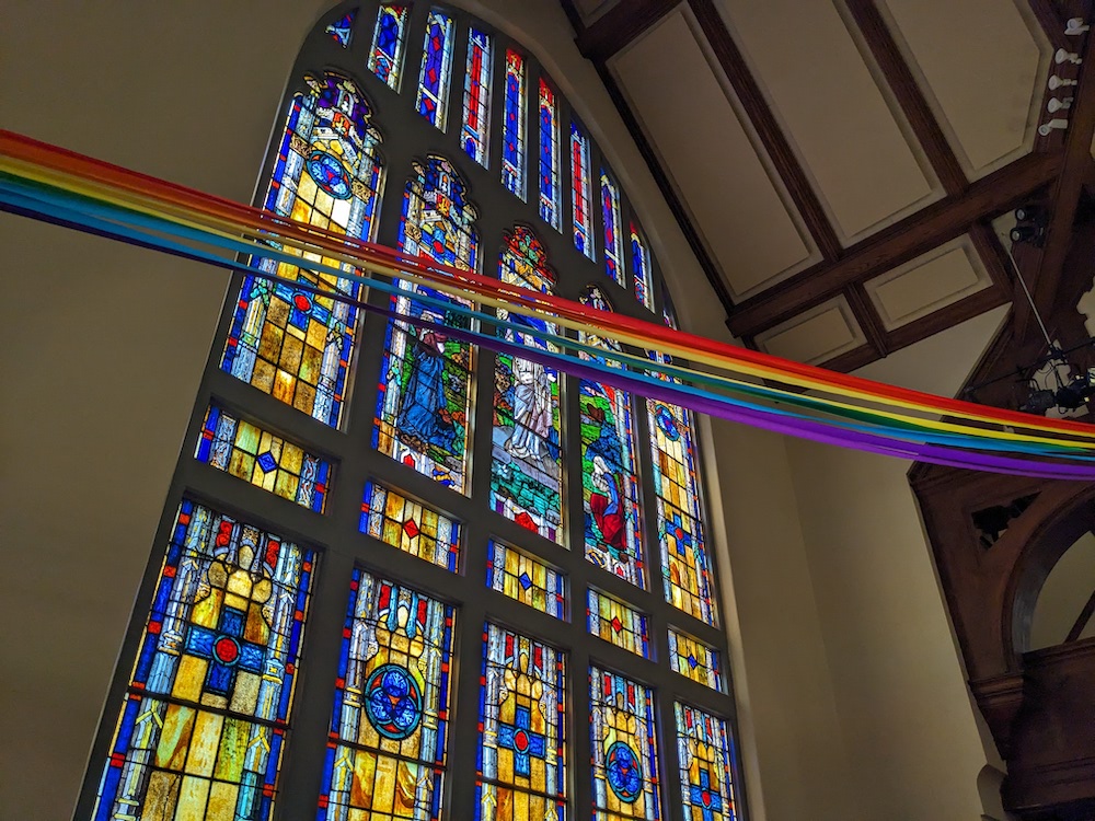 Stained glass church window bisected by rainbow ribbons