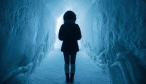 Person in an ice cave or tunnel with their back to the camera