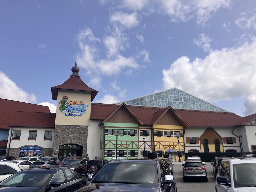 A German-themed inn with a parking lot in front and a glass pyramid structure in back