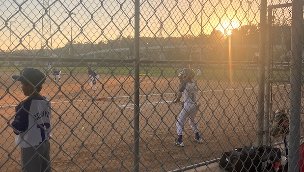 Children playing baseball at sunset