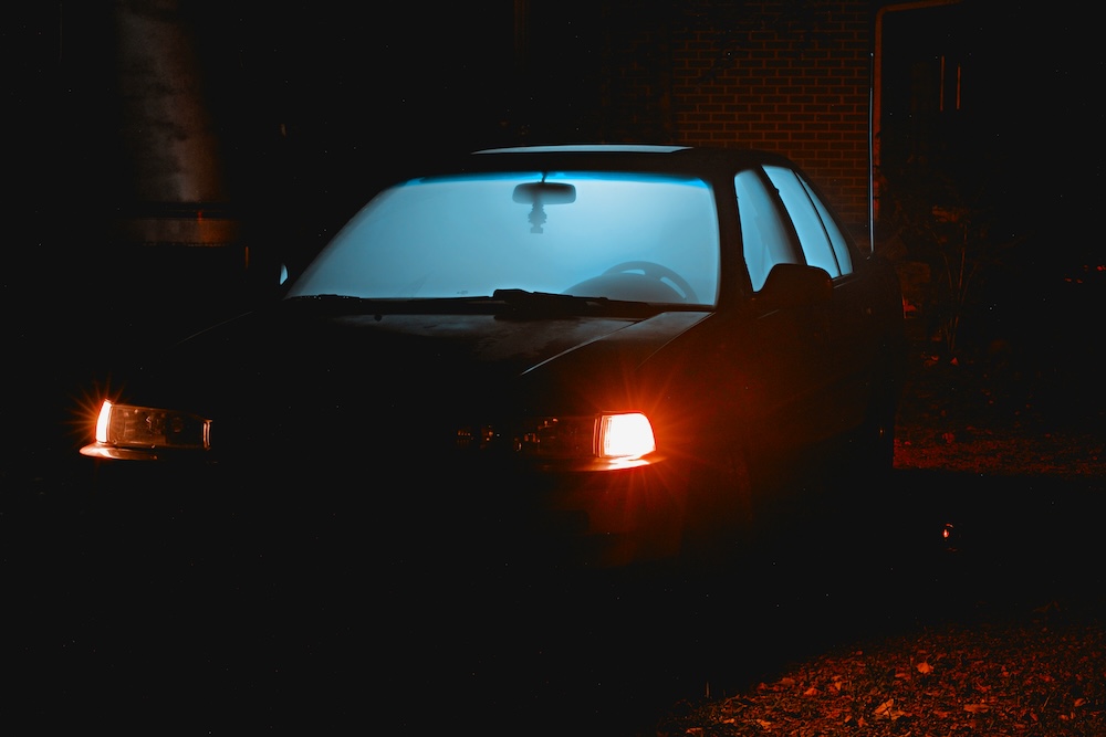 Car seen at night, lit up from within, headlights on