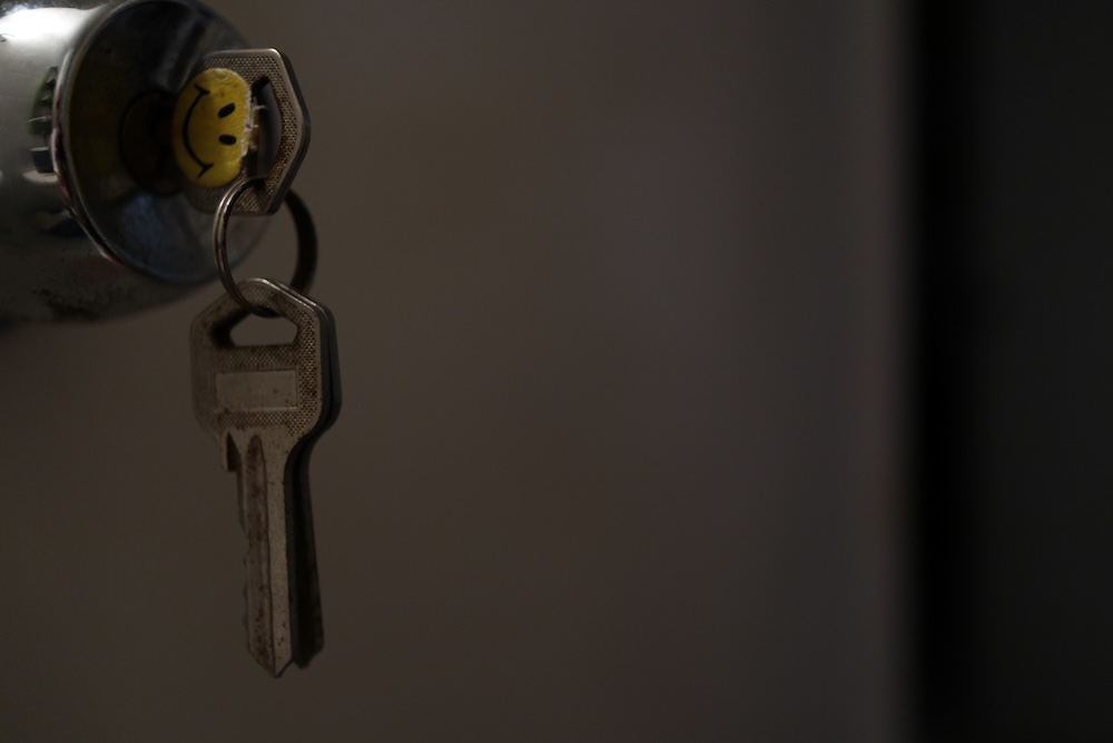 Key with a happy face sticker on it hanging from lock