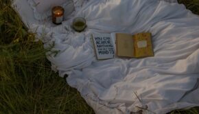 Book and candle on a blanket. The book says "You can do anything you put your mind to."