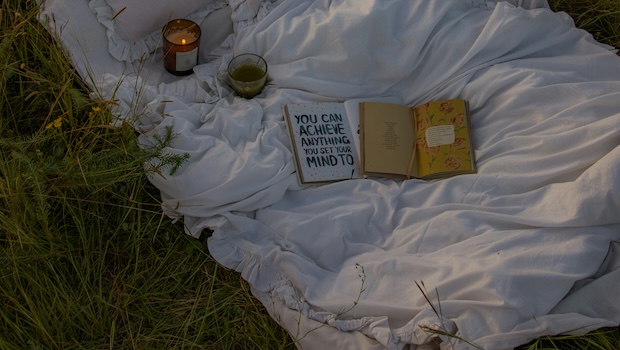 Book and candle on a blanket. The book says "You can do anything you put your mind to."