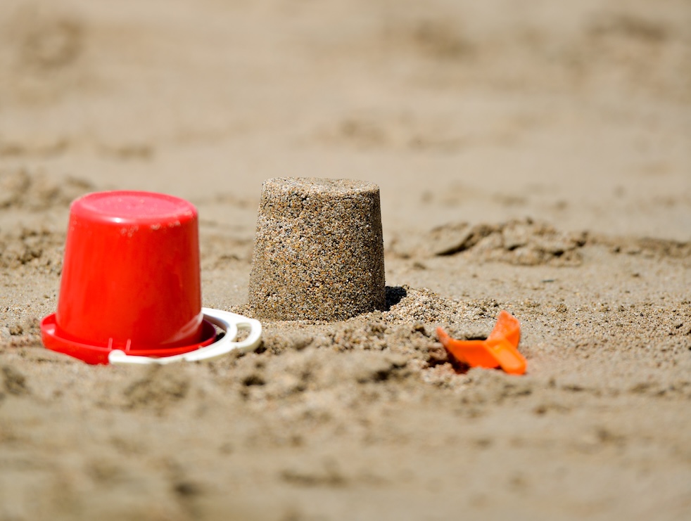 Red bucket overturned in sand